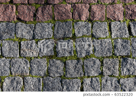 Paving stones made of natural stone. Paths for pedestrians. Beautiful square-shaped stones. Grass breaks through the rocks. The view from the top. Paving stones made of natural stone. Paths for pedestrians. Beautiful square-shaped stones. Grass breaks through the rocks. The view from the top. 63522320