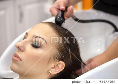 The hairdresser washes the hair of a young girl 63522568