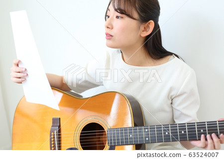 Woman practicing acoustic guitar 63524007