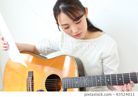 Woman practicing acoustic guitar 63524011