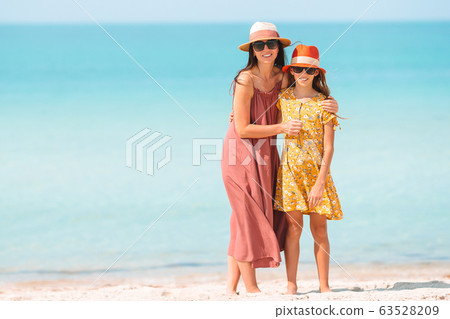 Beautiful mother and daughter at the beach enjoying summer vacation. Beautiful mother and daughter at the beach enjoying summer vacation. 63528209