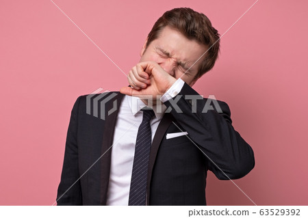 Handsome young man sneezing, isolated on pink 63529392