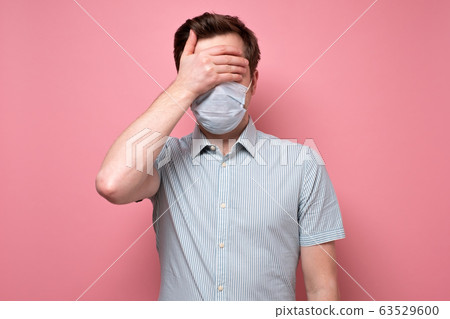 man in medical mask and covering eyes with hand. man in medical mask and covering eyes with hand. 63529600