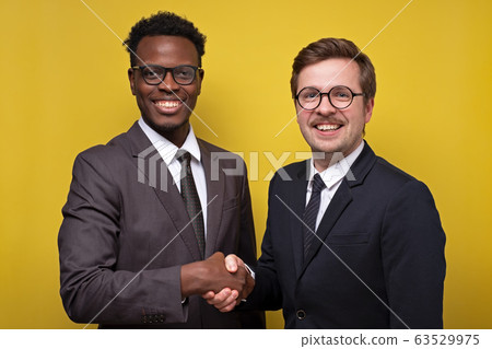 Two african and caucasian businessmen smiling and 63529975