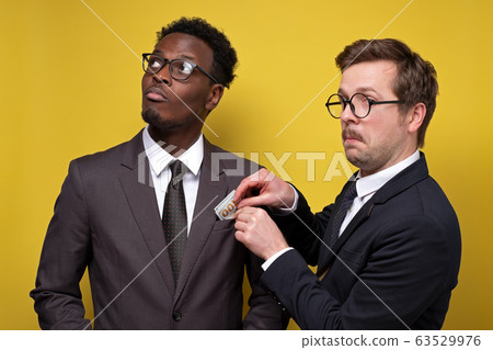 Young man in suit giving bribe to business partner 63529976