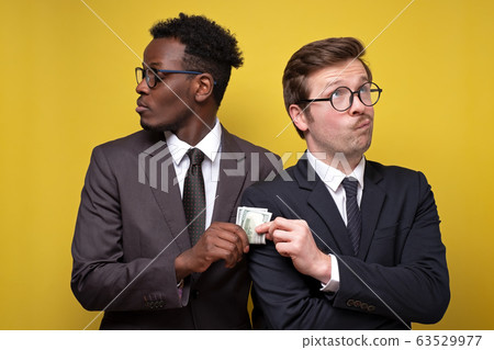 Young man in suit giving bribe to business partner 63529977