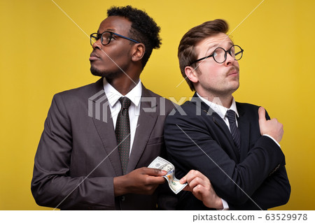 Young man in suit giving bribe to business partner Young man in suit giving bribe to business partner 63529978