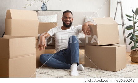 Many cardboard boxes from online store around smiling african american guy 63530248