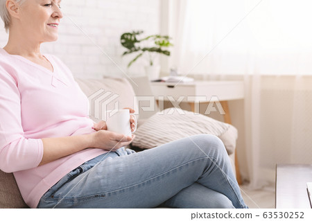 Senior lady enjoying hot fresh coffee at living room 63530252