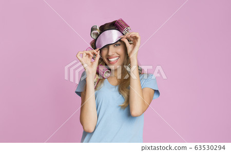 Housewife with curlers removes a sleep mask 63530294