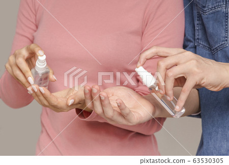 Virus Spread Prevention. Unrecognizable couple applying antibacterial spray on hands Virus Spread Prevention. Unrecognizable couple applying antibacterial spray on hands 63530305