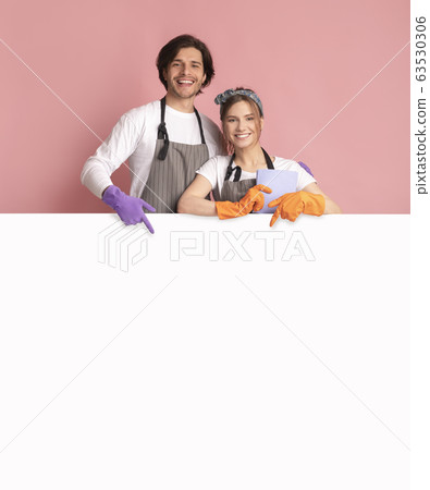 Smiling Couple Wearing Cleaning Gloves And Pointing At White Advertisement Board Smiling Couple Wearing Cleaning Gloves And Pointing At White Advertisement Board 63530306