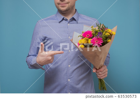 Unrecognizable man in blue shirt holding flowers Unrecognizable man in blue shirt holding flowers 63530573