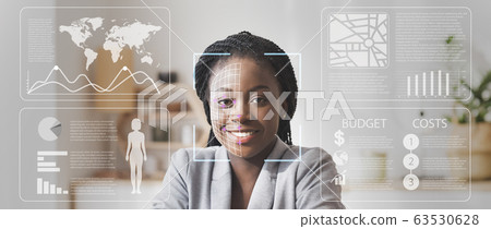 Face scanning of African American businesswoman in defocused office with double exposure of information on screen Face scanning of African American businesswoman in defocused office with double exposure of information on screen 63530628