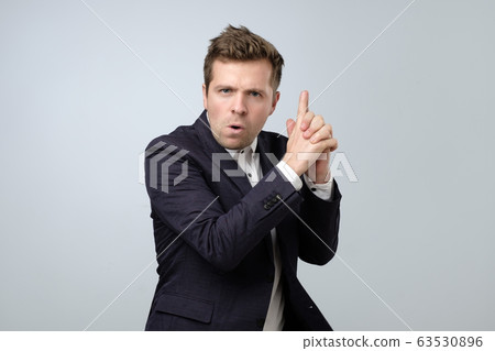 Young businessman doing a gun gesture getting Young businessman doing a gun gesture getting 63530896