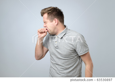 Young caucasian man having strong cough as illness 63530897