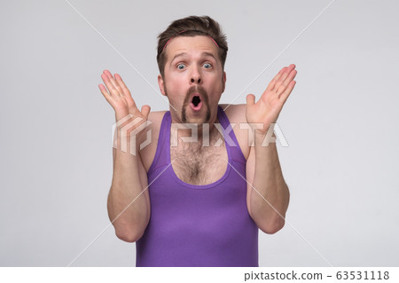 Young man wearing sport purple shirt shocked with Young man wearing sport purple shirt shocked with 63531118