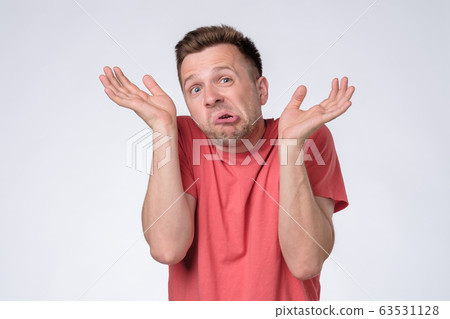Clueless, funny looking young man holding arms out 63531128