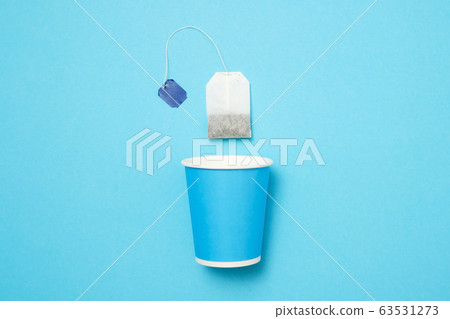 Blue paper cup with tea bag on blue wall. Blue paper cup with tea bag on blue wall. 63531273