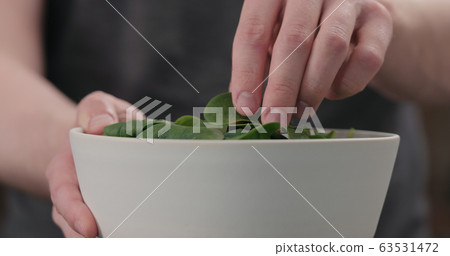 man show fresh spinach leaves in white bowl closeup man show fresh spinach leaves in white bowl closeup 63531472