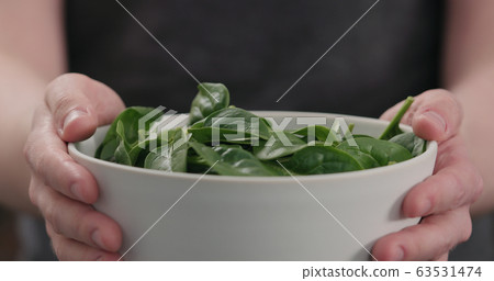 man show fresh spinach leaves in white bowl closeup man show fresh spinach leaves in white bowl closeup 63531474