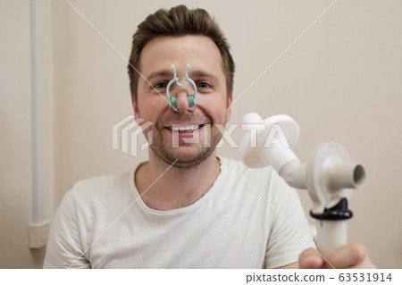 Young man testing breathing function by spirometry Young man testing breathing function by spirometry 63531914