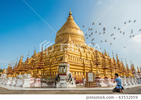 Tourist sitting and praying to Shwezigon pagoda an iconic ancient pagoda in Bagan kingdom of Myanmar. 63532059