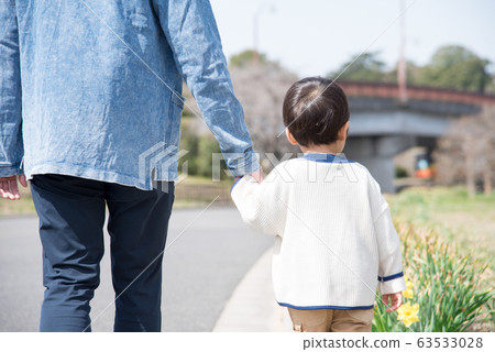 Parent and child holding hands and walking 63533028