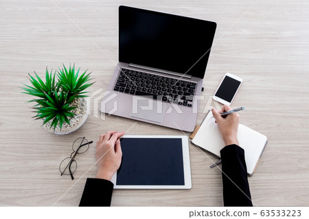 The woman is working with various office gadgets 63533223
