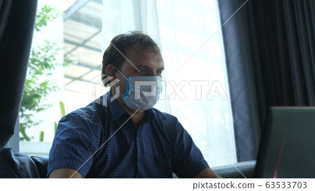 Man works from home in quarantine wearing a face mask 63533703