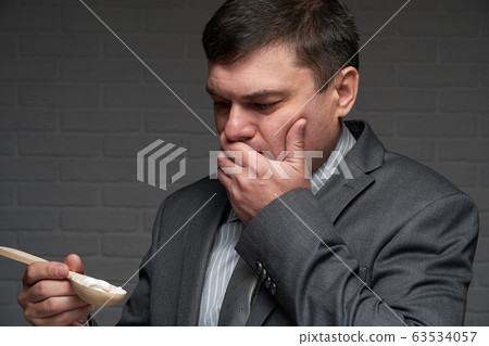 a man with spoon full of pills, sneezes or coughs a man with spoon full of pills, sneezes or coughs 63534057