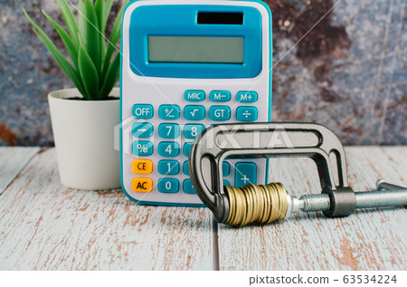 calculator and stacking coin squeezing in a clamp 63534224