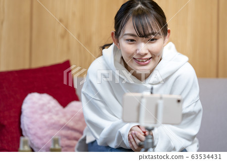 在智能手機上拍攝視頻的女性Youtuber股票經紀人的圖像 在智能手機上拍攝視頻的女性Youtuber股票經紀人的圖像 63534431