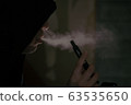 Vaper / A man smoking an electronic cigarette in a dark room 63535650