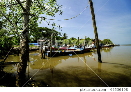fisherman boat moored near wooden jetty over blue sky background 63536198