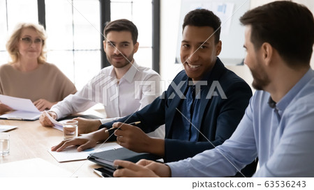 Smiling diverse colleagues joke discussing ideas at meeting 63536243