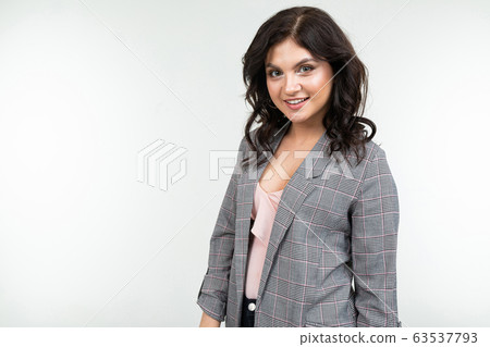 confident brunette girl in a checkered gray jacket on a white background with copy space 63537793