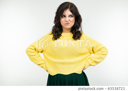 dissatisfied girl in a yellow sweater and green skirt on a white background dissatisfied girl in a yellow sweater and green skirt on a white background 63538721