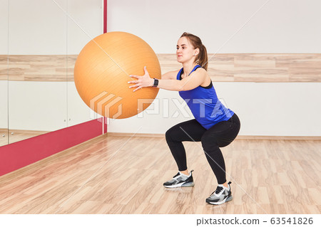 young woman is training by doing squats with fyt 63541826