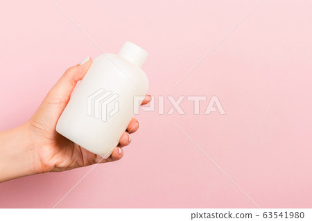 Close up of cosmetics bottle in female hand at Close up of cosmetics bottle in female hand at 63541980
