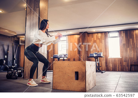 Shot of young woman working out with a box at the gym. Female athlete box jumping at a crossfit gym 63542597