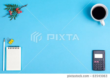 Flat lay of minimal workspace desk with notebook , pencil, coffee and green plant copy space on blue tone 63543063