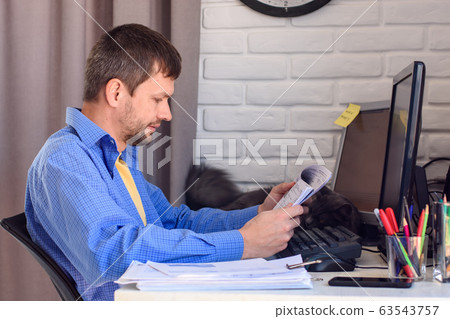 A man works remotely at home, reads documents at 63543757
