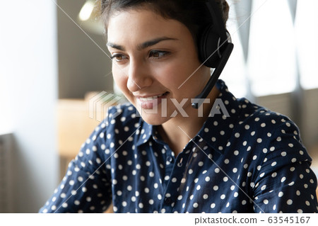Close up smiling Indian woman wearing headset working online Close up smiling Indian woman wearing headset working online 63545167