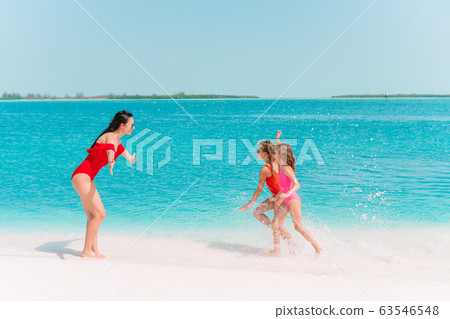 Adorable little girls and young mother on tropical white beach Adorable little girls and young mother on tropical white beach 63546548