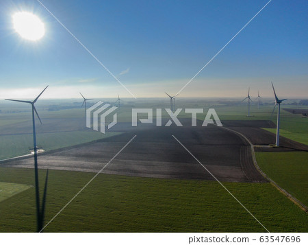Aerial view of wind turbines on agricultural fields during blue winter day 63547696