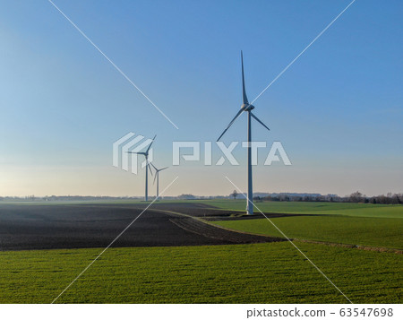 Aerial view of wind turbines on agricultural fields during blue winter day 63547698