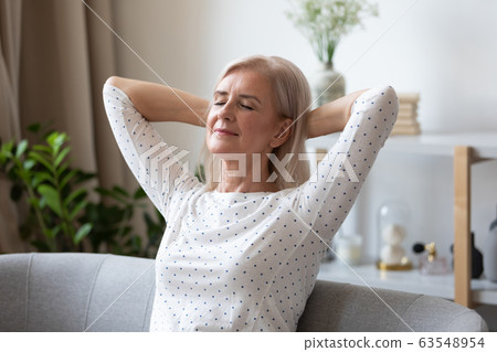 Peaceful middle aged pleasant woman daydreaming on comfortable sofa. Peaceful middle aged pleasant woman daydreaming on comfortable sofa. 63548954