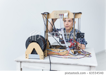 Education, children, technology concept - teen boy is printing on 3d printer. Education, children, technology concept - teen boy is printing on 3d printer. 63554540