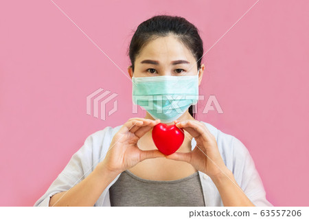 Young asian woman wore protective masks against virus and air pollution,holding red heart Young asian woman wore protective masks against virus and air pollution,holding red heart 63557206